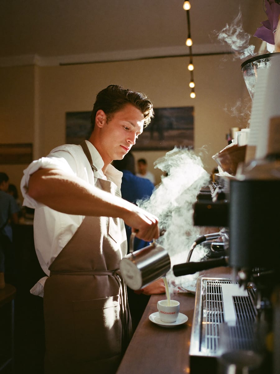 Café-Inhaber hinter seiner Espressomaschine